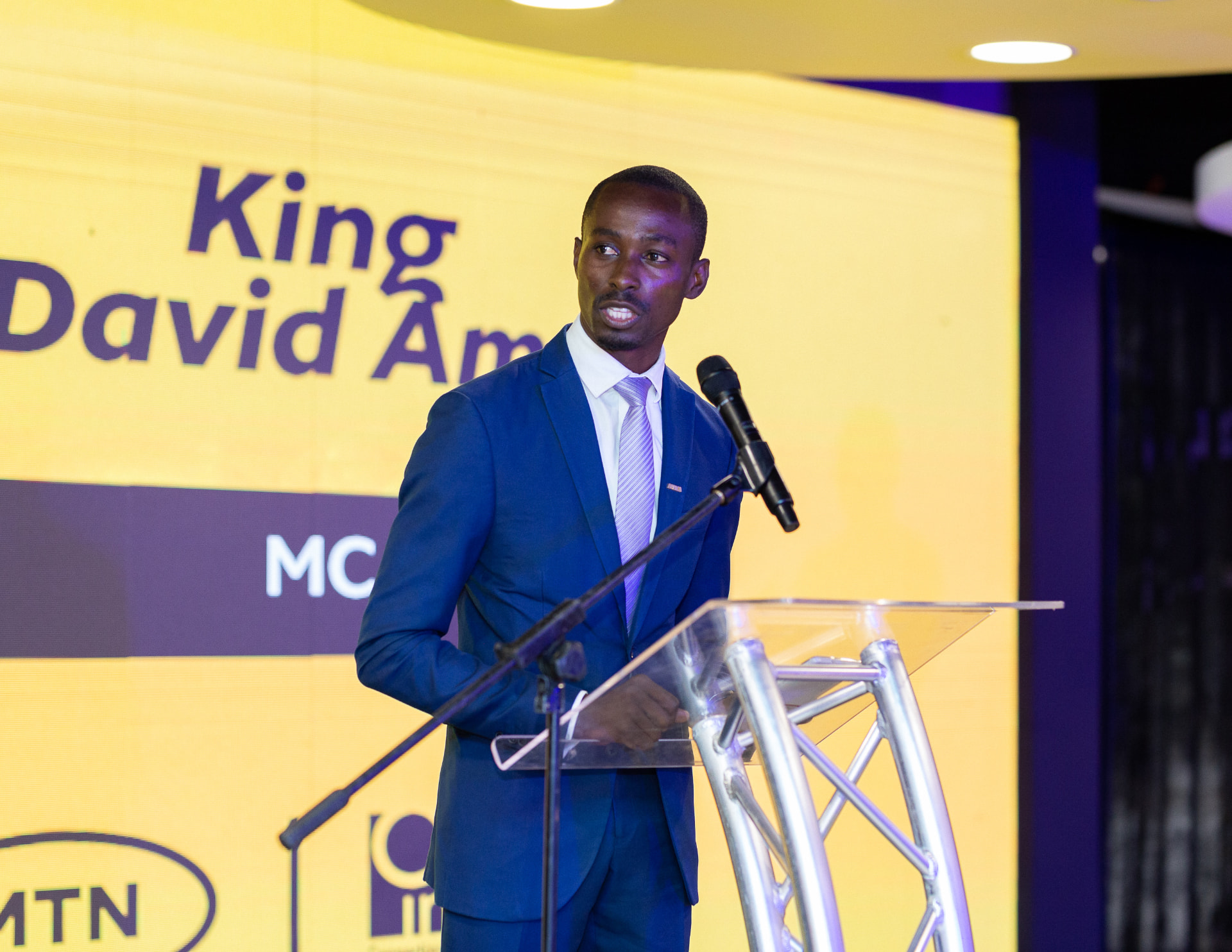 King David Amo hosting from a podium in front of a large event screen